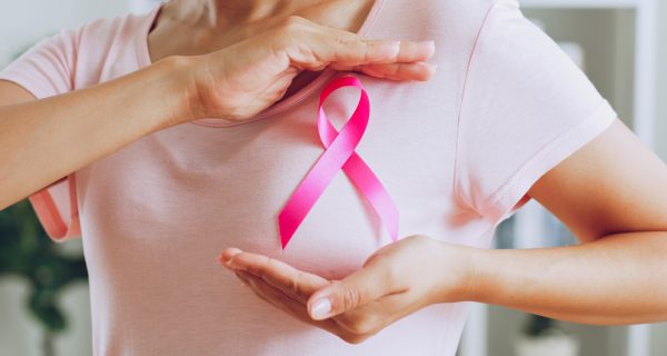 Asian woman show pink ribbon as sign of October Breast Cancer Awareness month